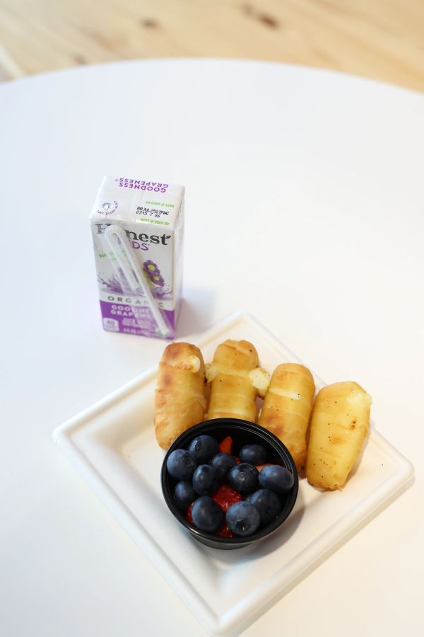 Breakfast with cheese sticks, blueberries, and grape juice box.