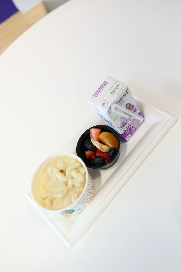 Tray with macaroni and cheese, fruit cup, and purple beverage carton.