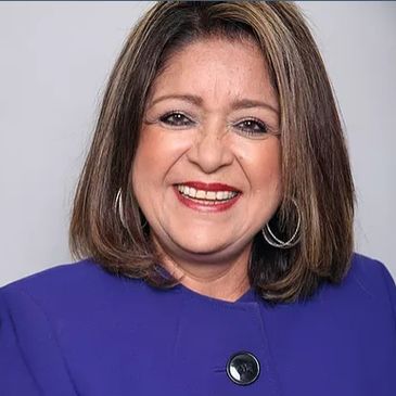 Smiling woman in a purple blazer with hoop earrings.
