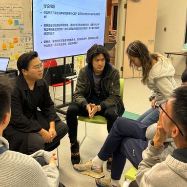 A group discussion in a classroom with a presentation screen in the background.