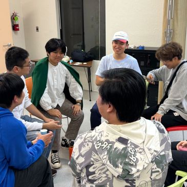A group of young men sitting in a circle having a discussion indoors.