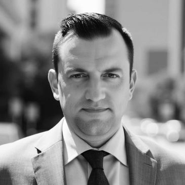 Professional man in a suit standing outdoors in an urban setting.