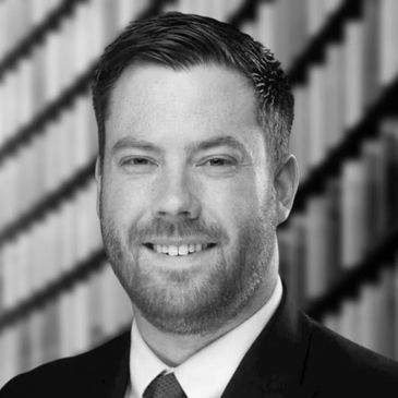 Professional headshot of a smiling man with a beard and green tie.