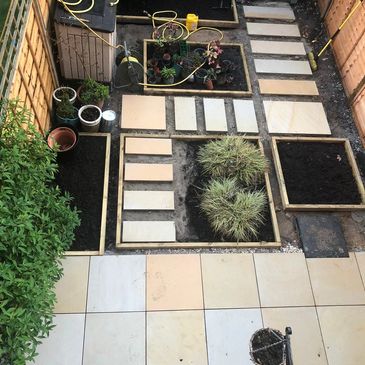 A neatly arranged garden with tiled paths and plant beds.