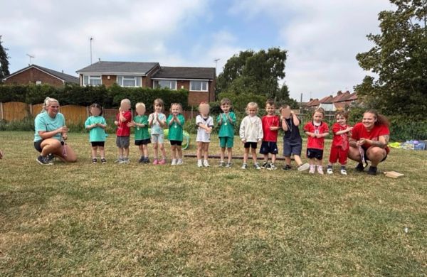 Group of children and two adults posing on a field.