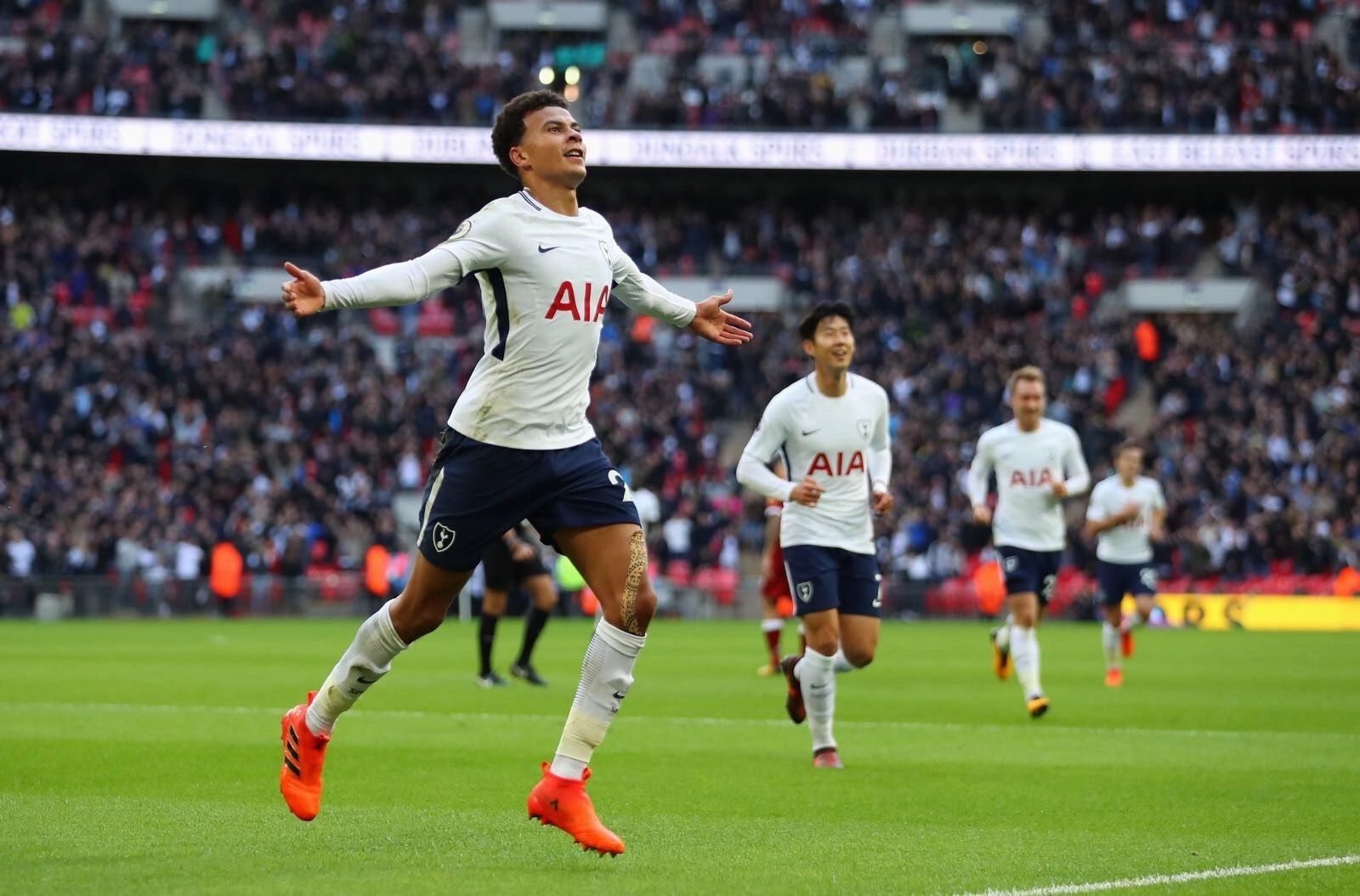 Tottenham player celebrates a goal with arms outstretched during a match.