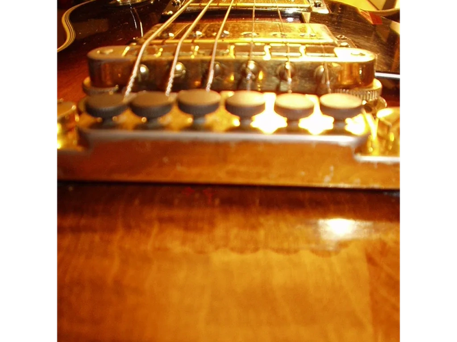 Close-up of a LES PAUL guitar bridge and strings.
