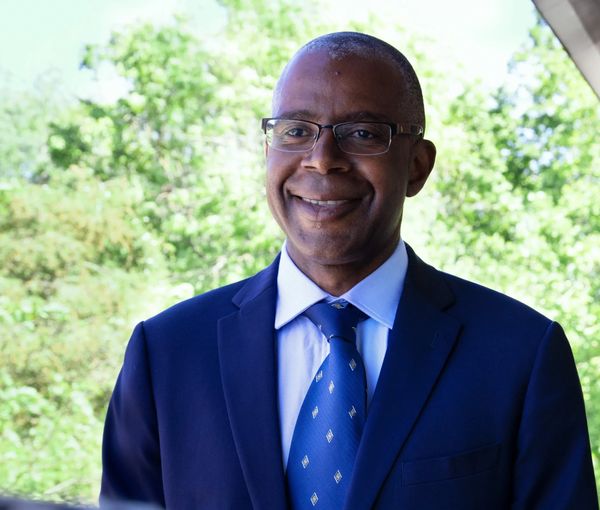 Smiling man in a blue suit and tie outdoors.