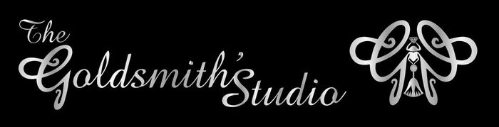 Close-up of a gold ring with a green gemstone held by tweezers, with two blurred gold rings in the background.