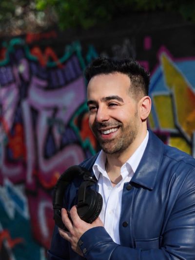 Man holding headphones with graffiti background.