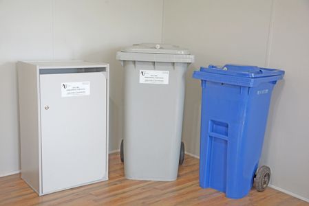 Three different waste bins placed indoors against a wall.