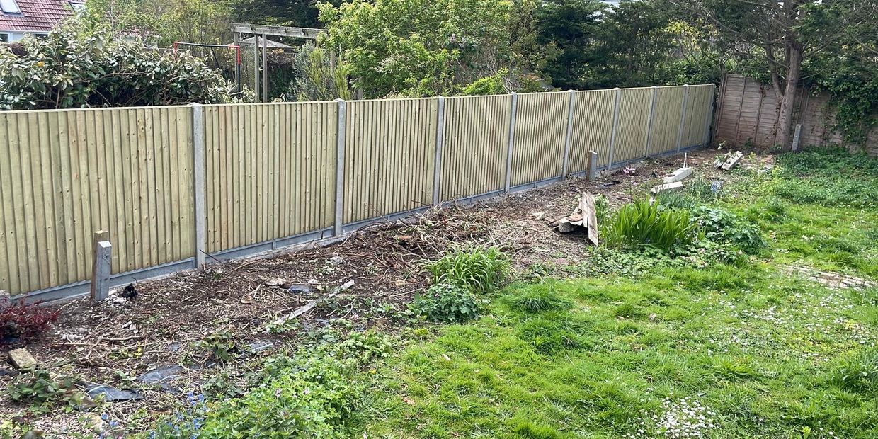 New wooden garden fence with grassy yard.