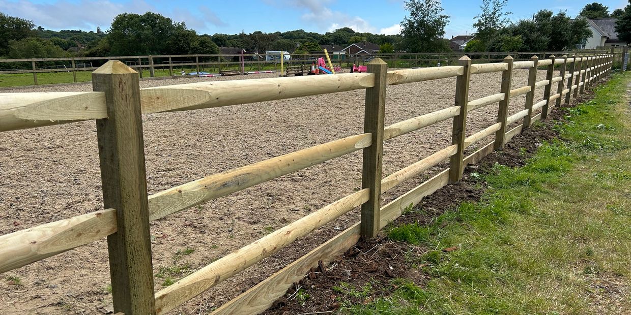 New wooden fence alongside a dirt field.