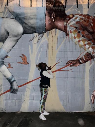 A child interacts with a large mural of two figures on a wall.