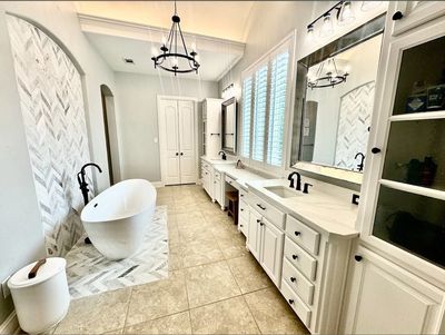 Bathroom featuring freestanding tub and large vanity with new countertop, mirrors, and chandelier.