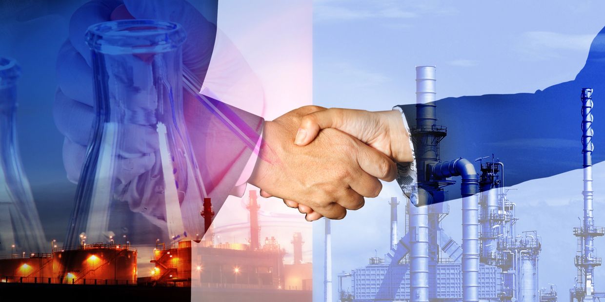 People shaking hands with chemical plants in the background representing chemical compliance