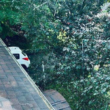 Roof with shingles and a white car in the background.