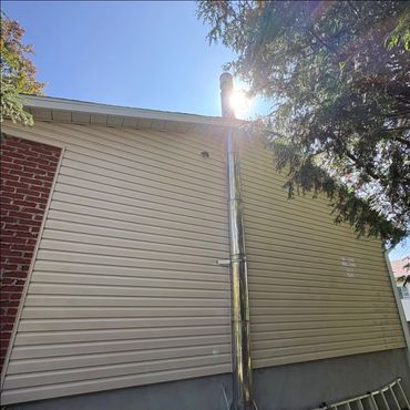 Shiny metal chimney pipe attached to house siding.