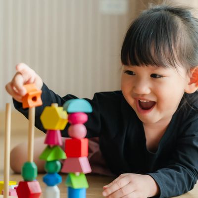 A happy child playing with colorful stacking toys indoors.