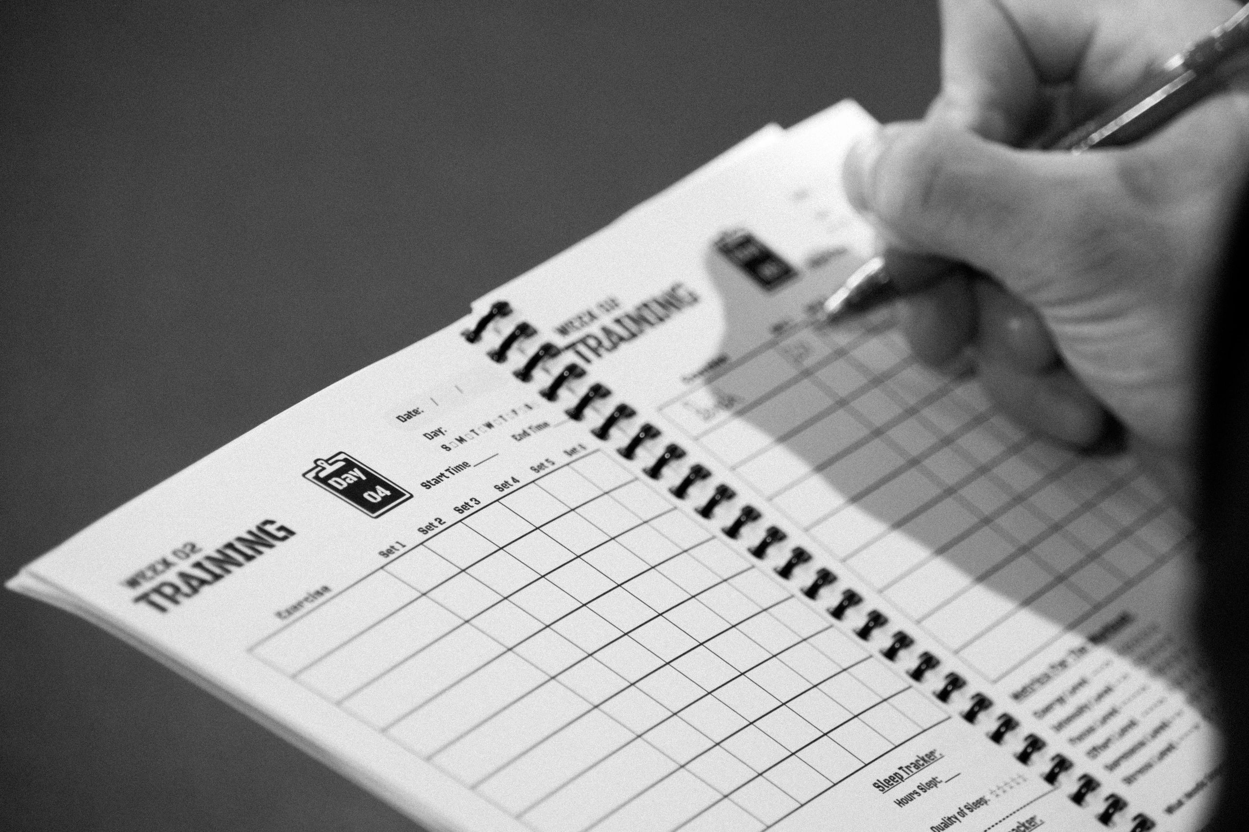 Hand writing on a training log notebook.