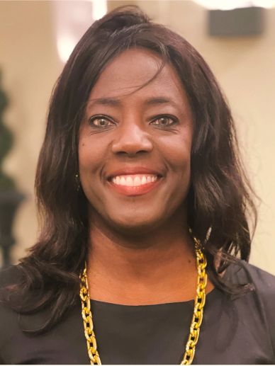 Smiling woman with dark hair wearing a gold chain and black top.