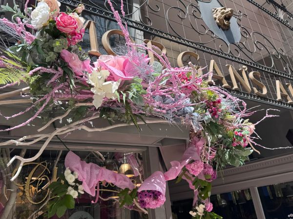 Floral decoration with pink flowers and greenery on a storefront.