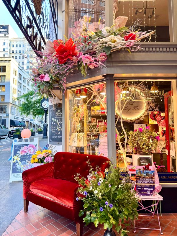 Red velvet sofa outside a flower shop with floral decorations.