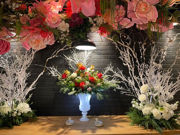 flower install at top of photo and white snowy branches below, two centerpieces and glass urn 