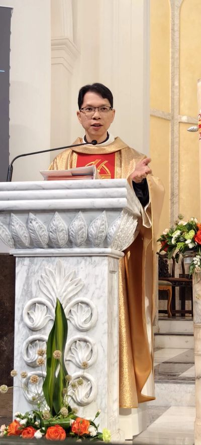A priest giving a sermon at a decorated marble pulpit inside a church.