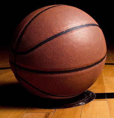 A close-up of a basketball on a wooden court.