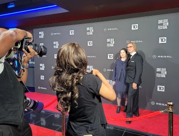 Photographers capturing a couple on the red carpet at a film festival.