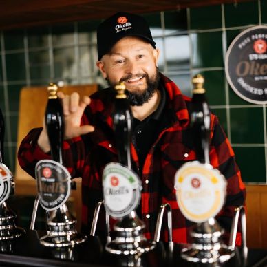 A bartender serving beer at a pub with a friendly smile.