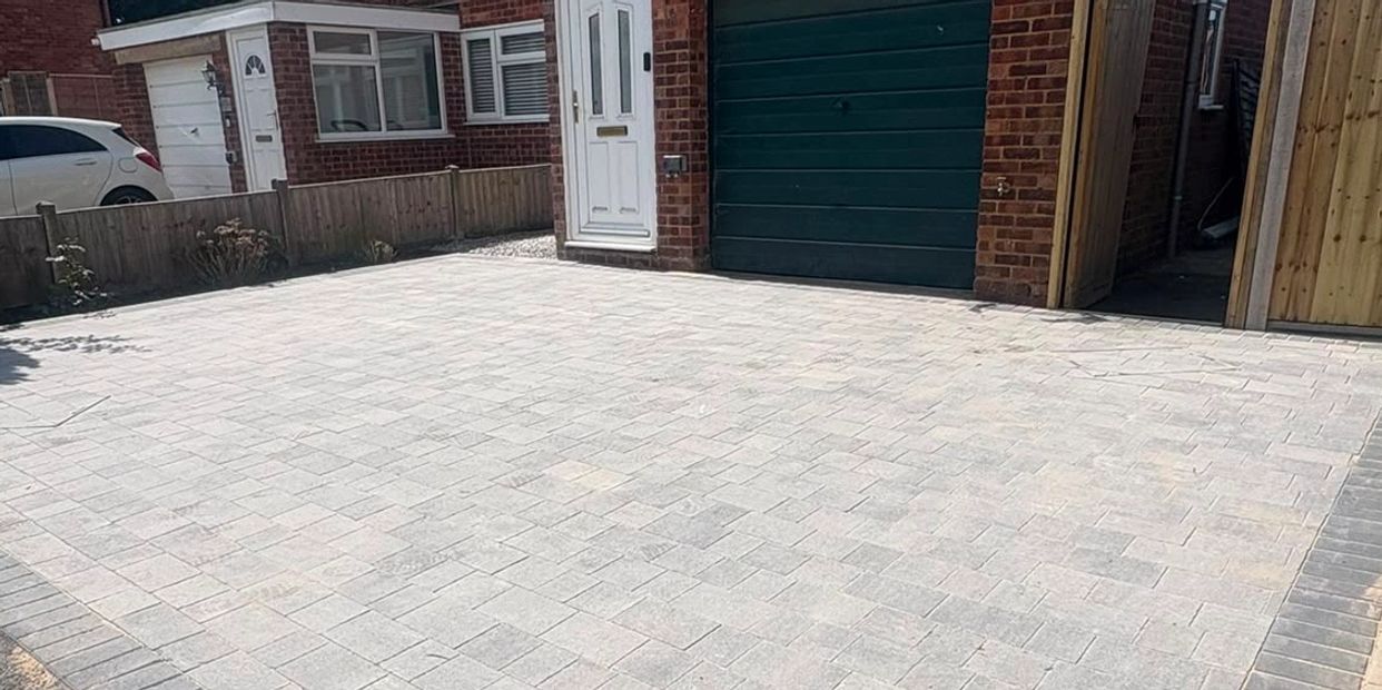 Clean, newly paved driveway in front of a brick house.