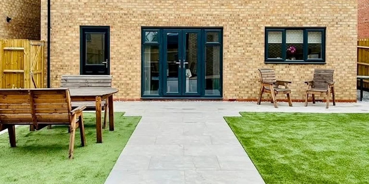 Neat backyard with wooden furniture and green artificial grass.