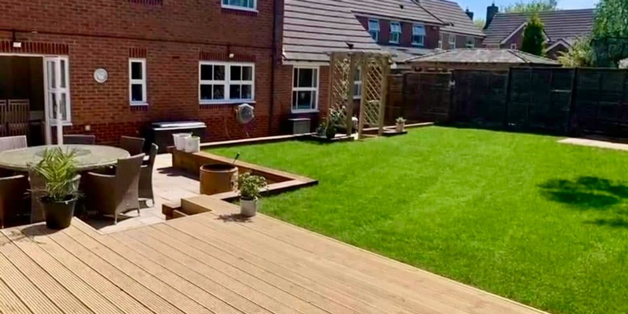Well-kept backyard with lawn, patio, and wooden deck.