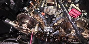 Close-up of a car engine's timing chain and camshaft gears.