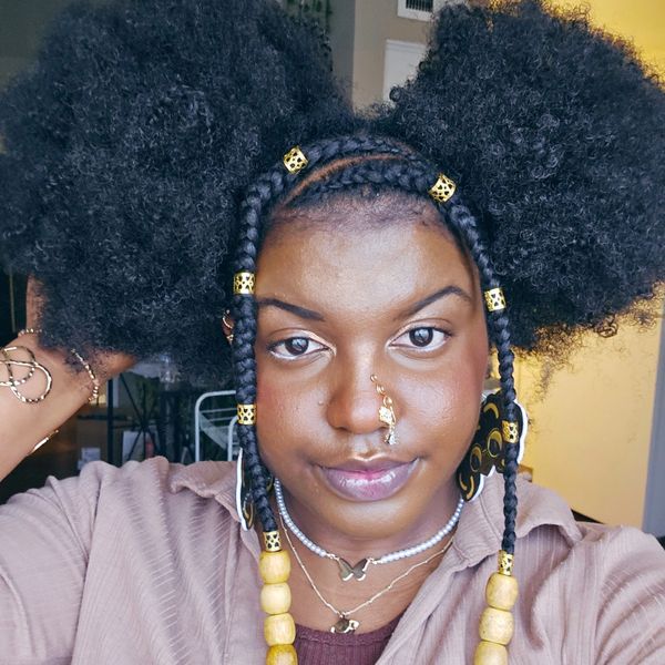 Woman with braided hair and large natural puffs adorned with golden beads.