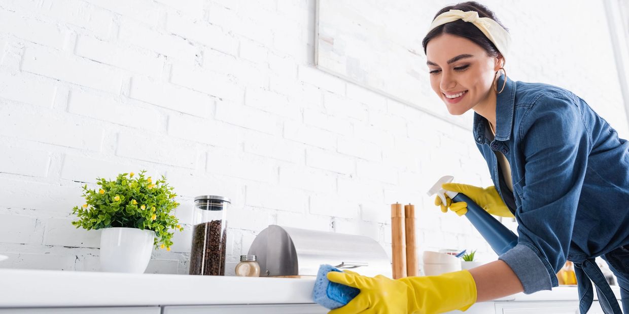 A woman diligently cleaning a kitchen counter, ensuring a spotless and hygienic cooking space.