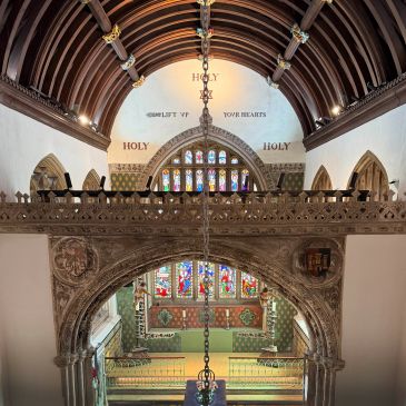 Interior view of a historic church with arched wooden ceiling and stained glass windows.