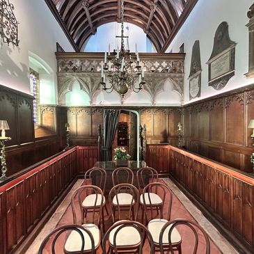 Historic chapel interior with wooden paneling and chairs.