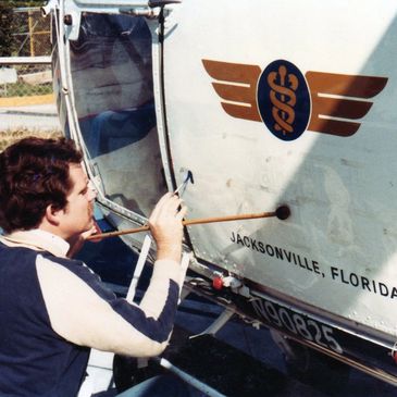 A man painting a medical emblem on a Jacksonville, Florida helicopter.