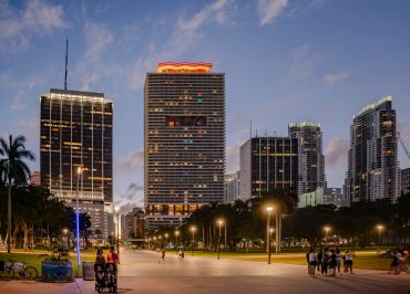 City park at dusk with skyscrapers and people.