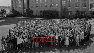 Large group holding BHC 2029 banner outdoors.