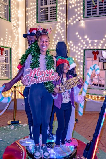 Group of three in Christmas attire holding festive signs.