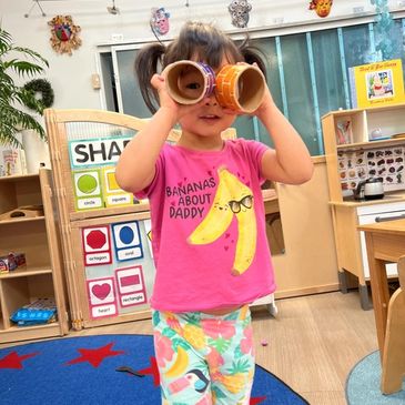 Little girl holding up two round toys around her eyes