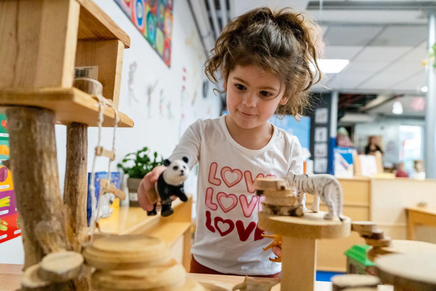 A young girl playing with a panda figure