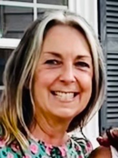 Smiling woman with gray-streaked hair.