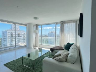 Bright modern living room with white furniture and large windows.