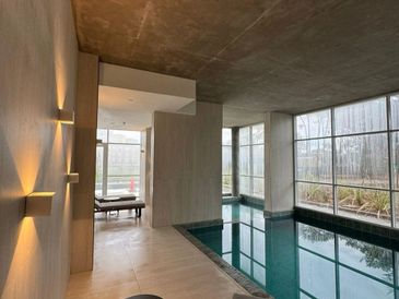 Modern indoor pool area with large windows and minimalist lighting.