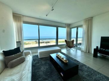 Modern living room with large windows overlooking the ocean.